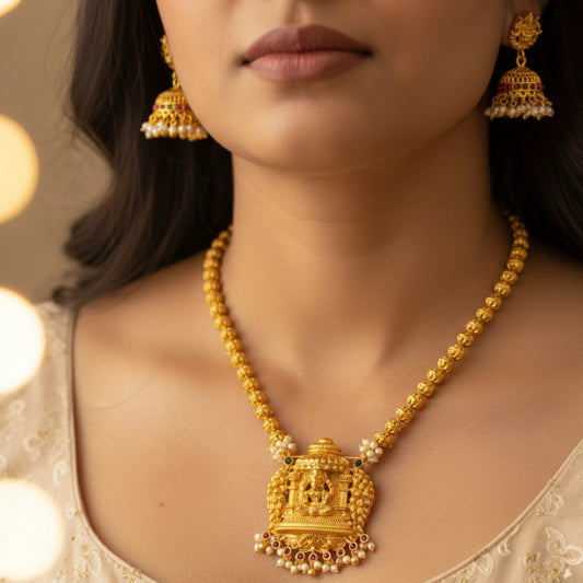 Woman wearing a antique gold finish necklace and earrings with a blurred background