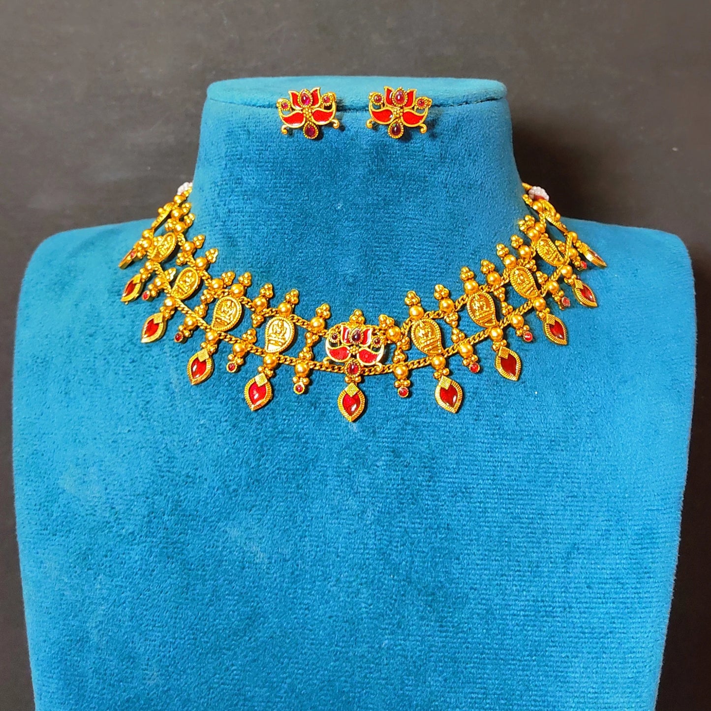 Traditional South Indian matte antique gold temple choker necklace with symmetrical red kemp stones, matching lotus earrings, and an adjustable thread dori