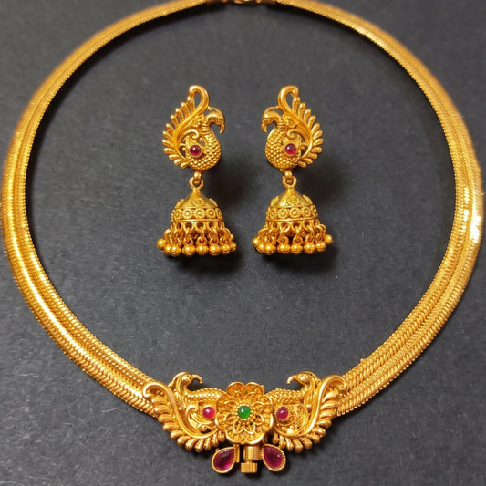 Traditional Indian temple jewelry set featuring a rigid gold peacock collar necklace and dangling Jhumkas in antique gold finish