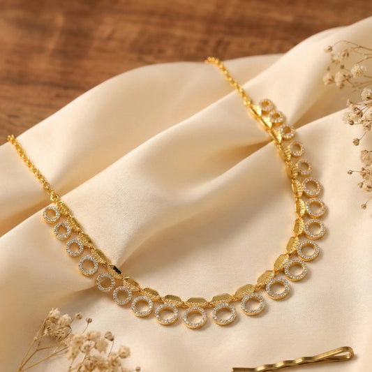Gold plated necklace with circular design on a beige fabric background
