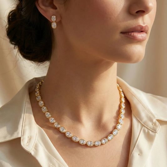 Close-up of a woman wearing a gold plated necklace and earrings with a neutral background