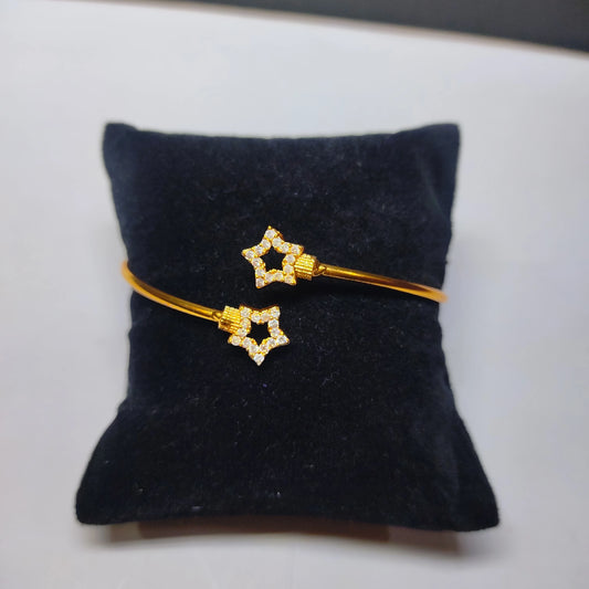 Gold plated bracelet with star-shaped ends on a black cushion