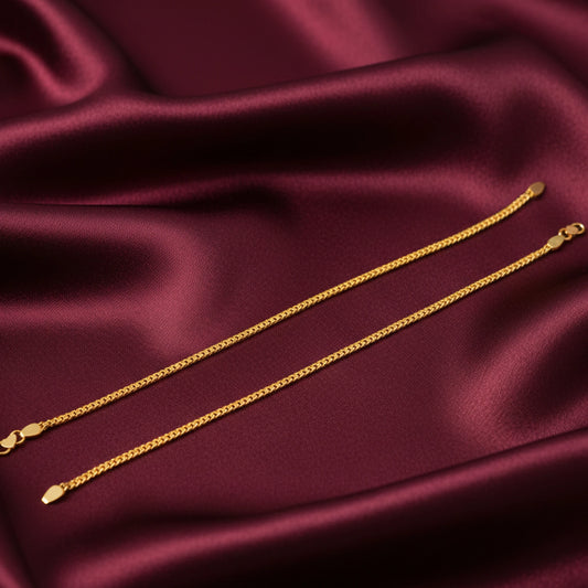 Gold plated anklets on a burgundy satin surface