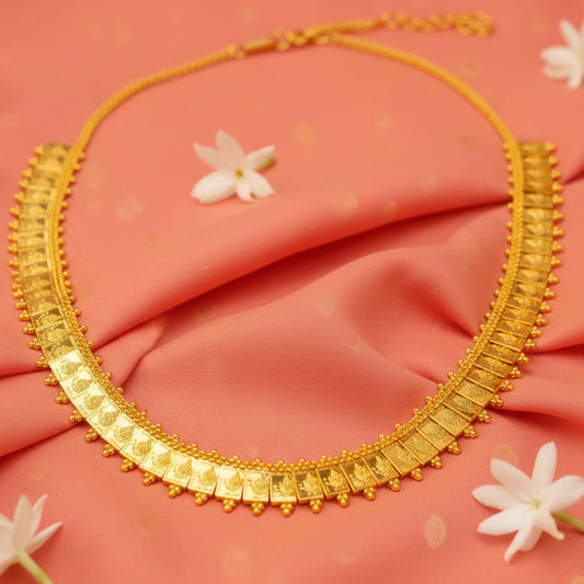 Gold plated Lakshmi square coin long haram necklace on a pink fabric background with white flowers