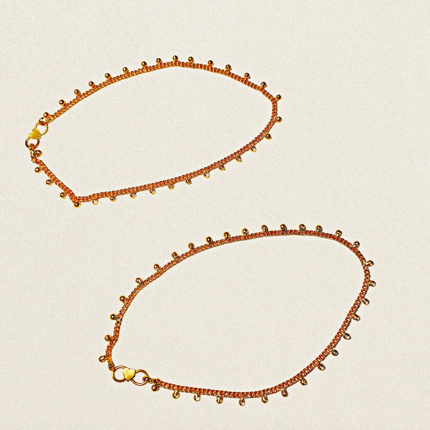 Two gold plated Anklets on a beige background