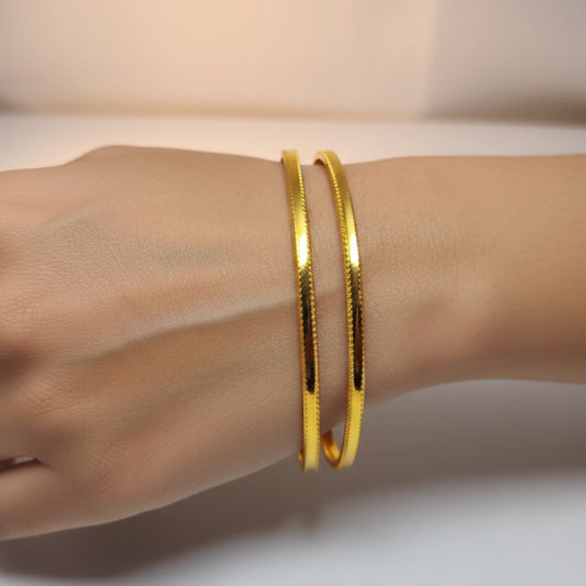Gold plated minimalist sleek daily wear bangles on a wrist against a neutral background