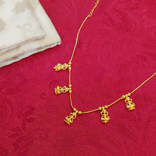 Gold plated necklace with Lakshmi Pendant on a red fabric background