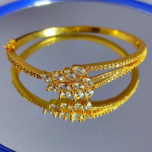 Gold plated bracelet with diamond-like stones on a reflective surface