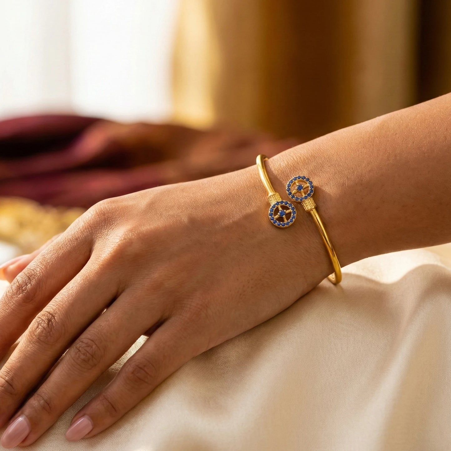 Gold plated bracelet with circular design on a person's wrist against a neutral background