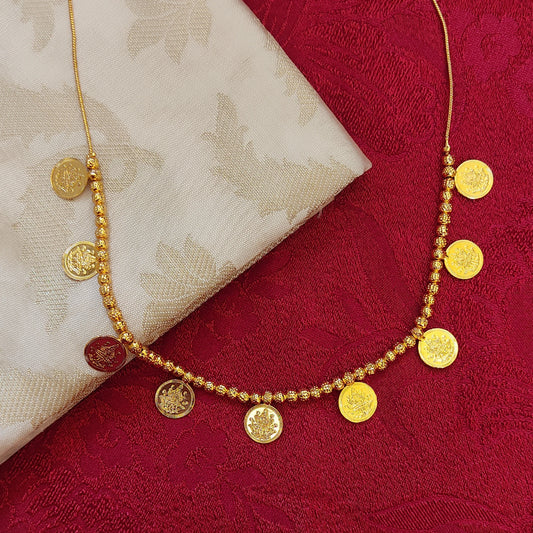 Gold plated necklace with circular lakshmi coin pendants on a red fabric background