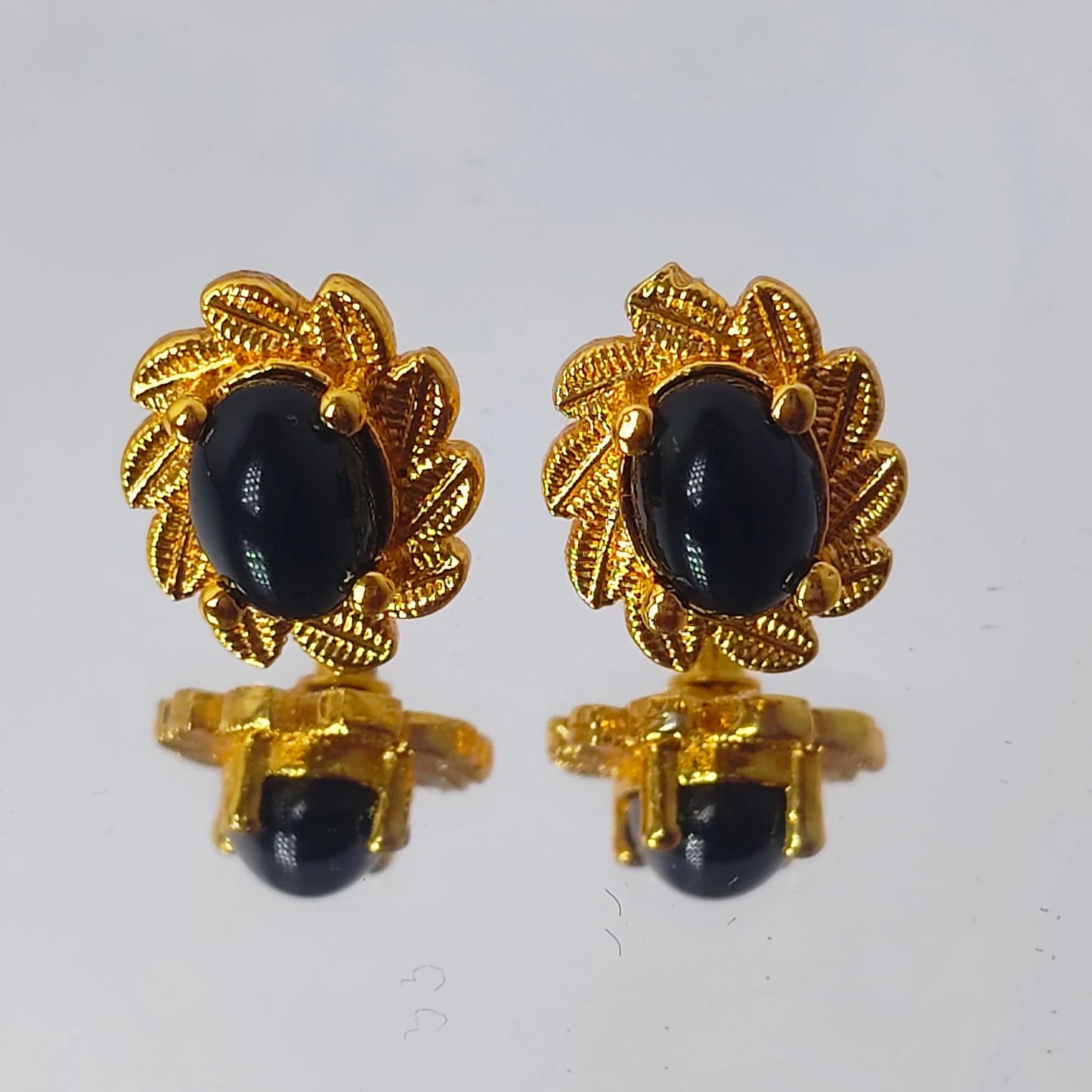 Pair of gold plated earrings with black stones on a white background