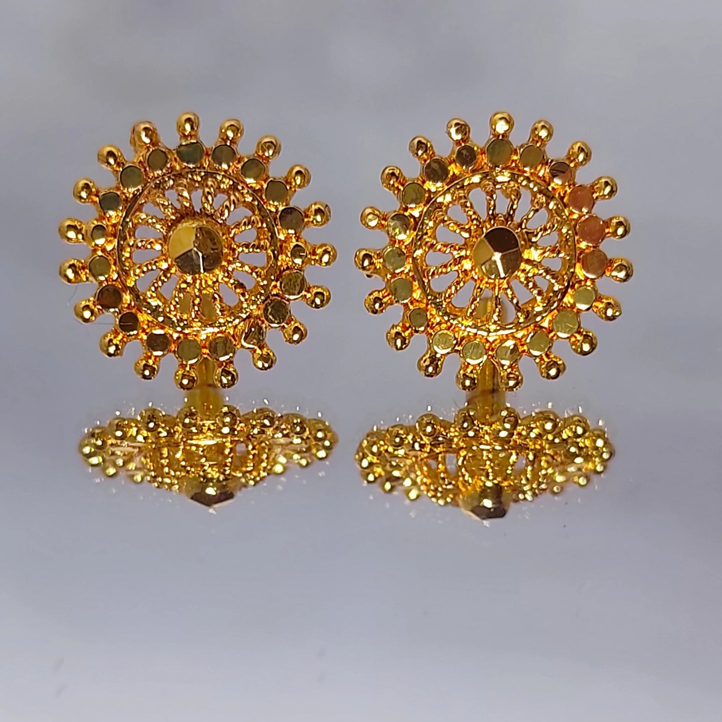 Pair of gold plated Mandala Art earrings on a light gray background