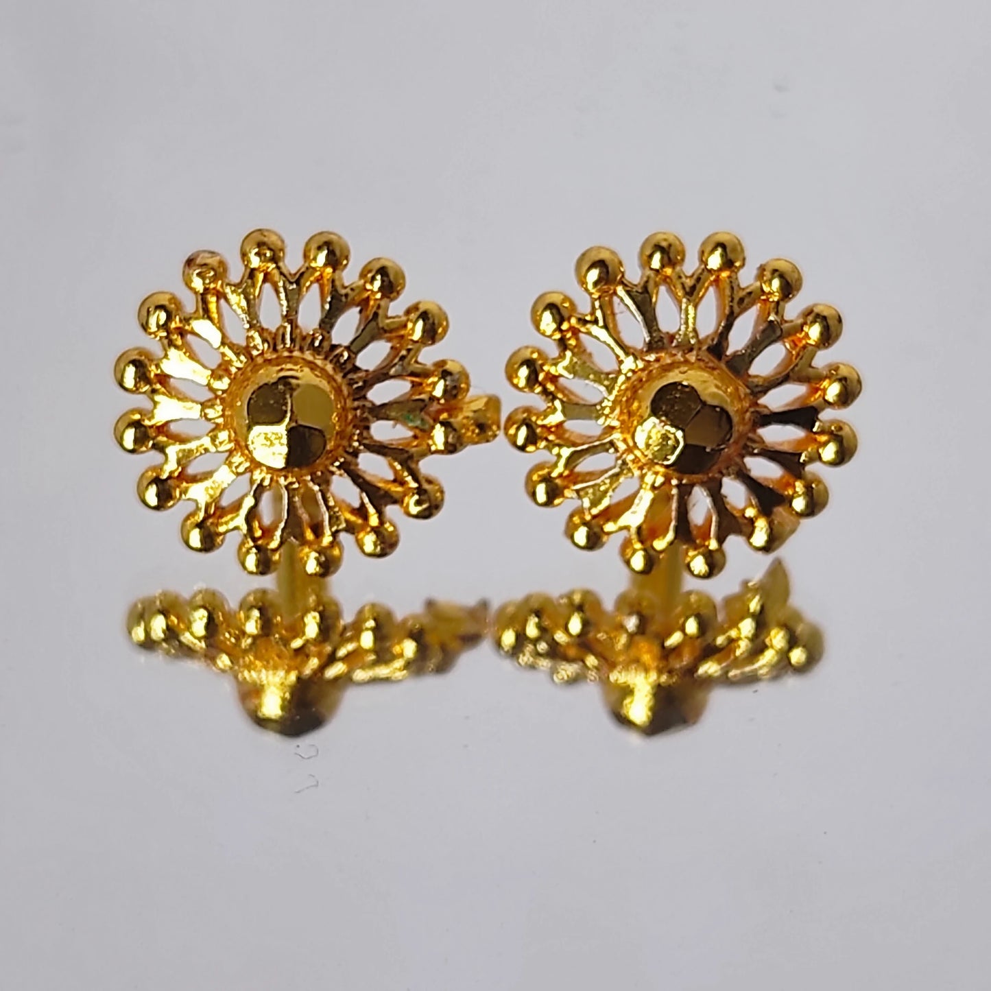 Pair of gold plated sunflower-shaped earrings on a light gray background
