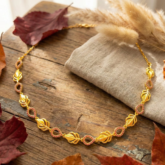 Gold plated necklace on a wooden surface with dried leaves