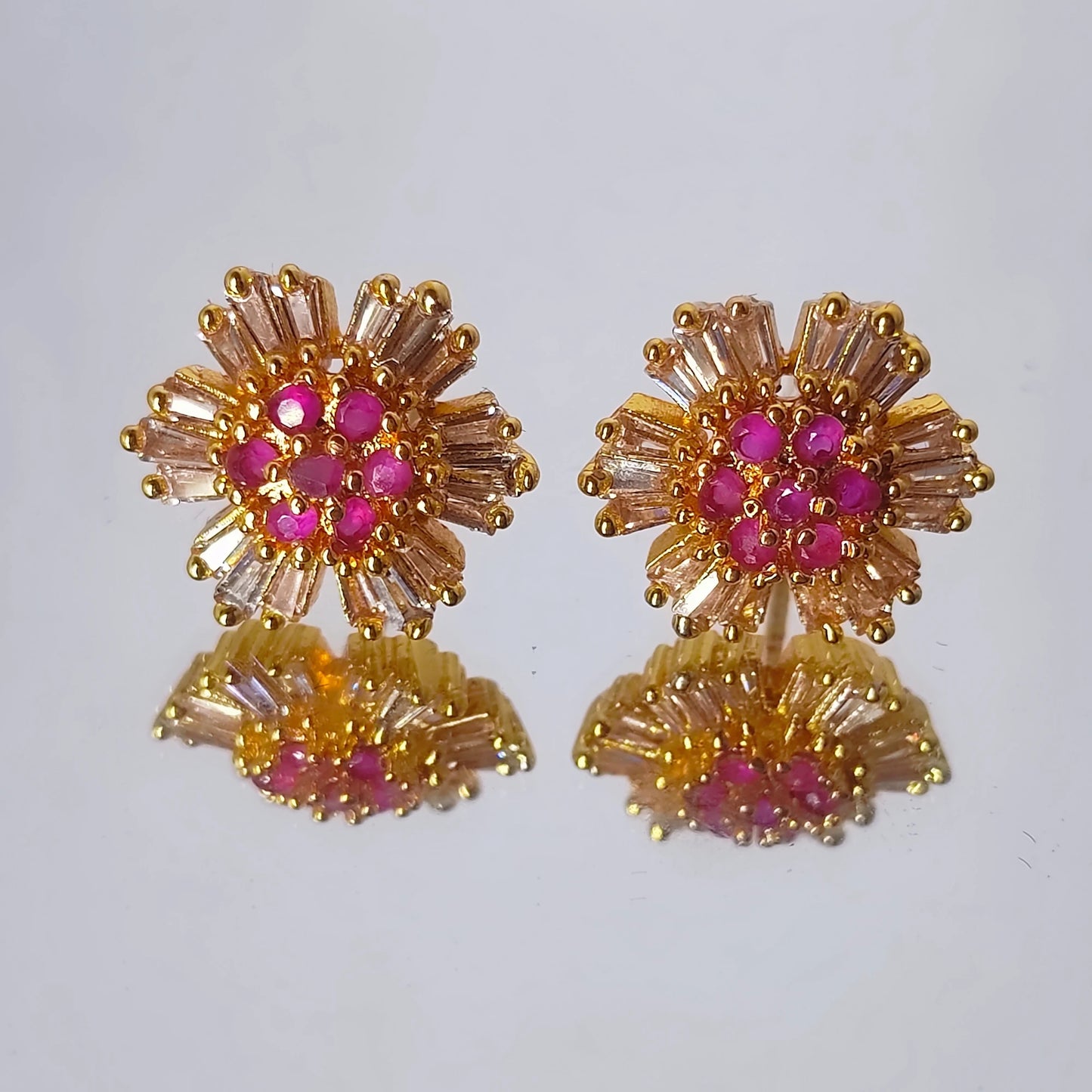 Pair of gold plated stud with pink floral earrings on a white background