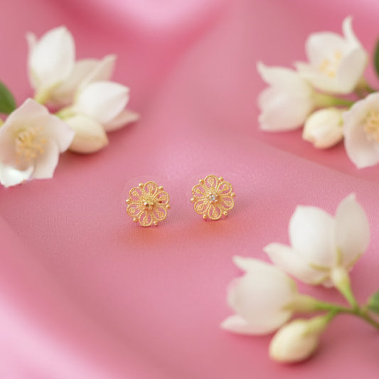 Gold plated floral earrings on a pink background with white flowers