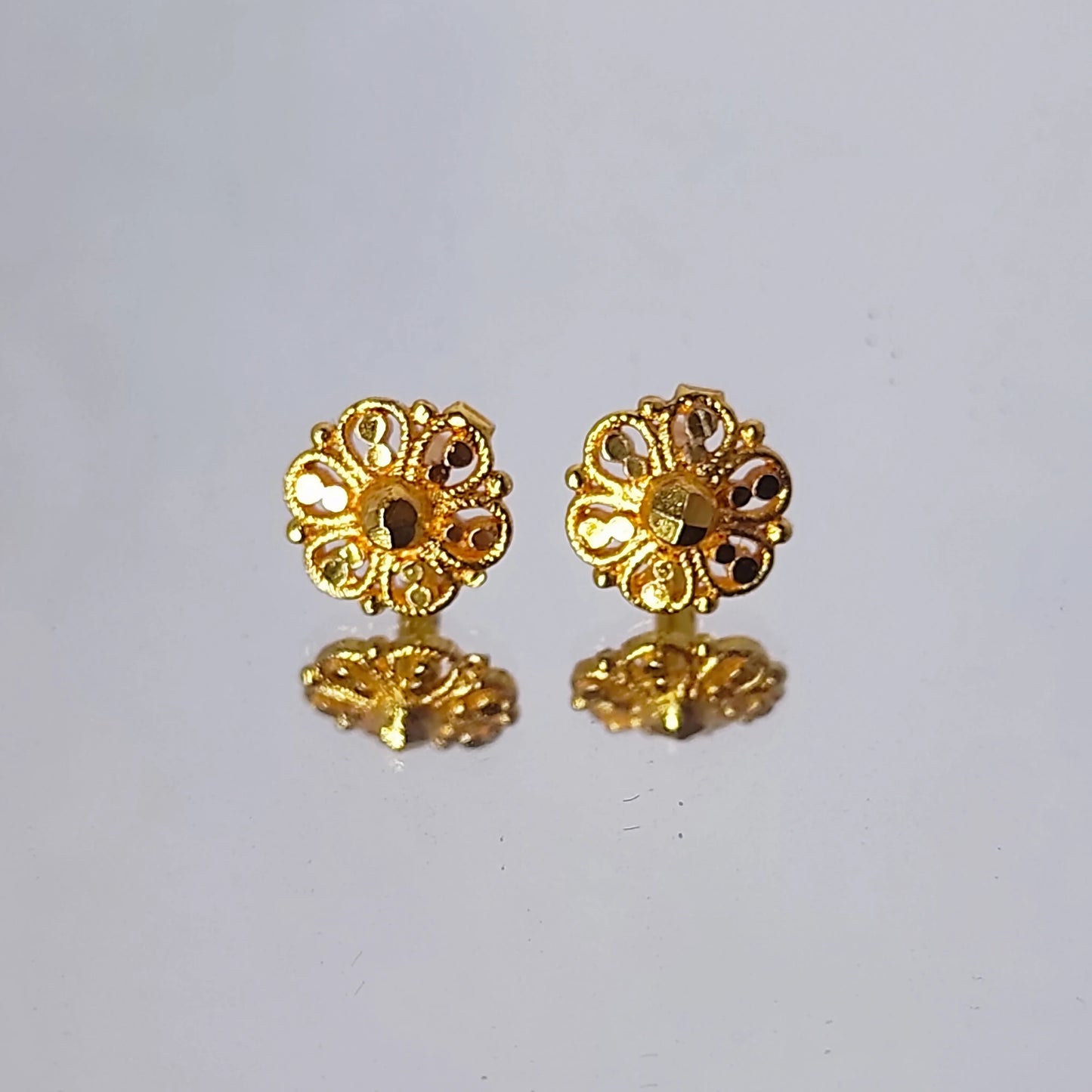 Pair of gold plated floral earrings on a light gray background