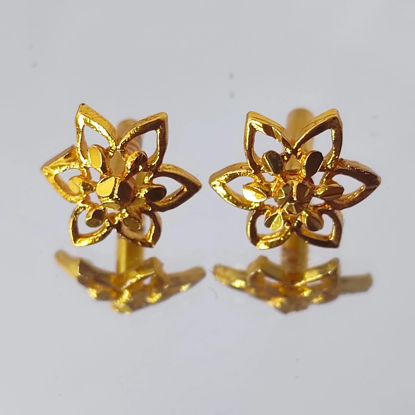 Pair of gold plated small floral earrings on a white background