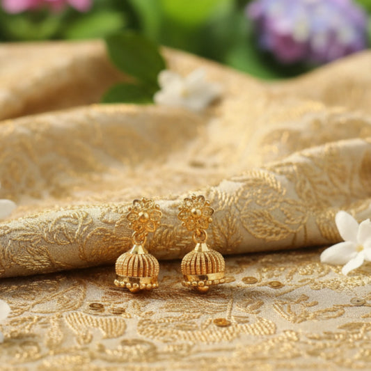 Gold plated earrings on a textured gold fabric background with flowers.