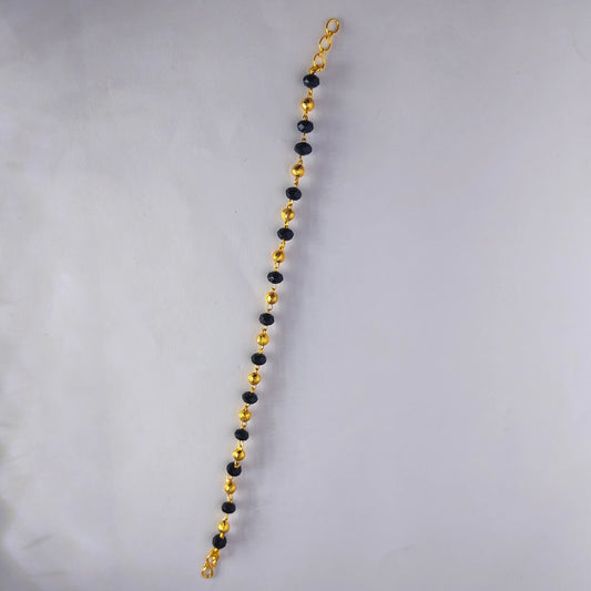 Gold and black beaded gold plated bracelet on a gray background