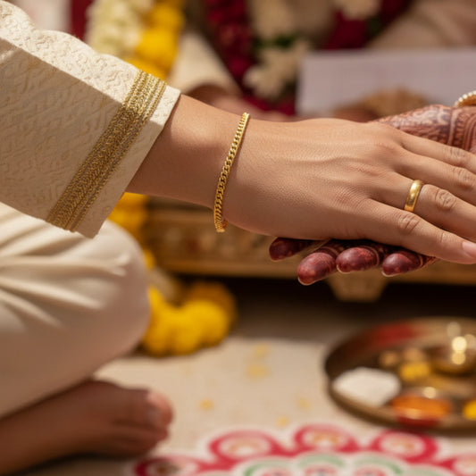 Two hands holding each other with gold plated curb link chain bracelet jewelry against a festive background
