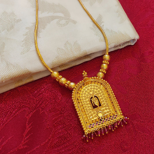 Gold plated traditional Krishna Temple Arch necklace with a pendant on a red fabric background