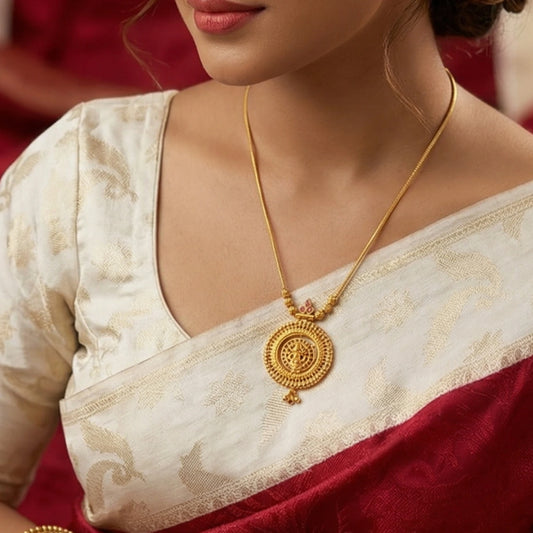 Woman wearing a gold plated necklace with circular pendant with a Lakshmi Motif with a red and white saree