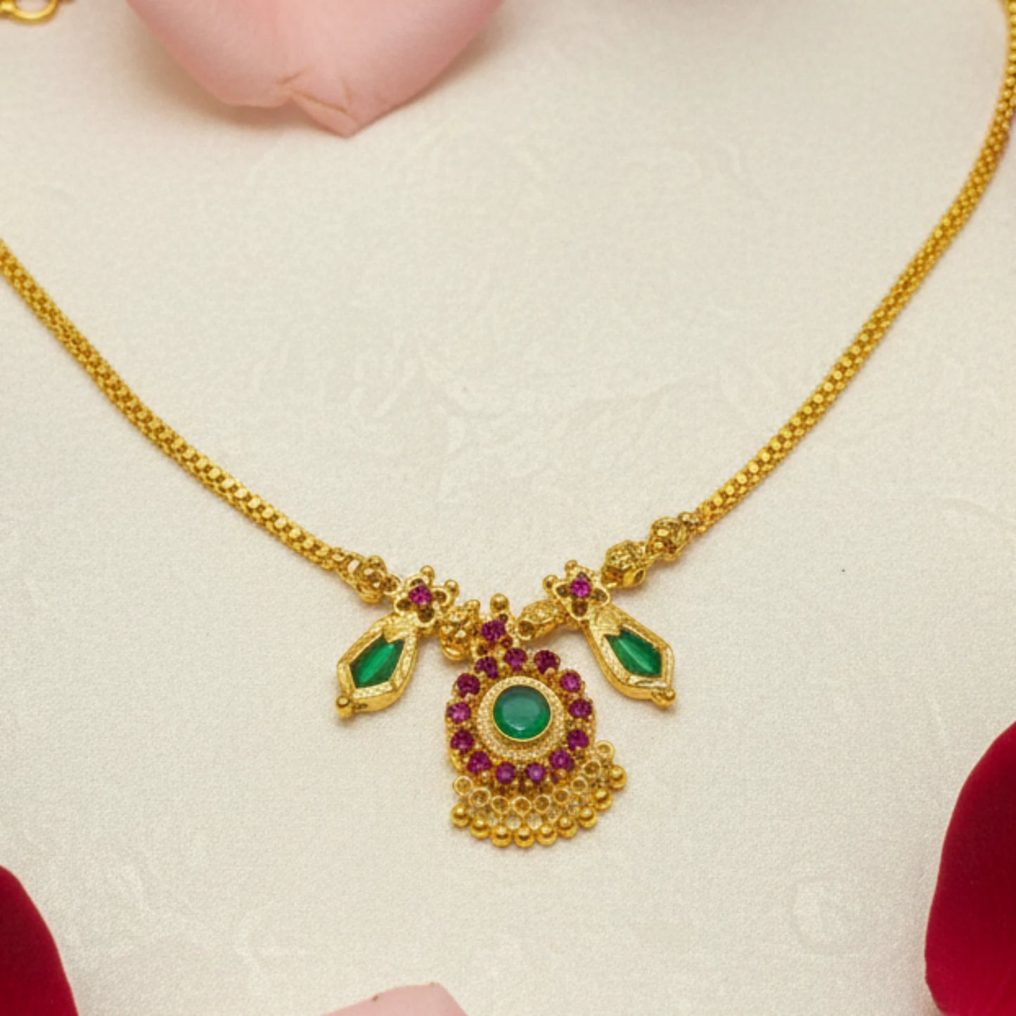 Gold plated choker necklace with green nagapadam and a pendant with ruby red gemstones on a beige background