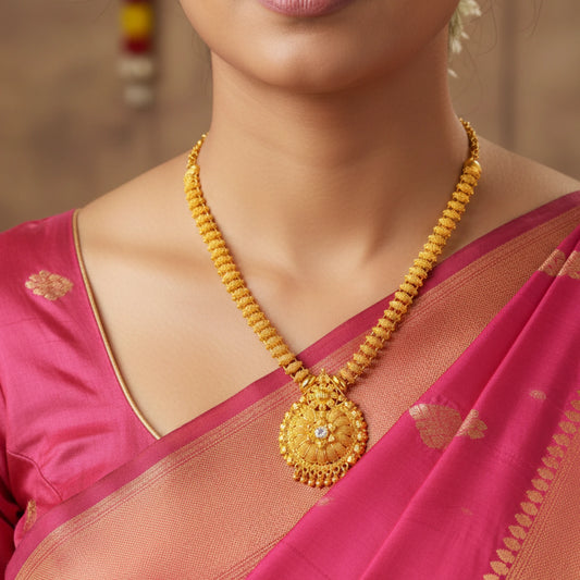 Woman wearing a gold plated necklace with a floral mandala pendant in a beaded chain with a pink saree