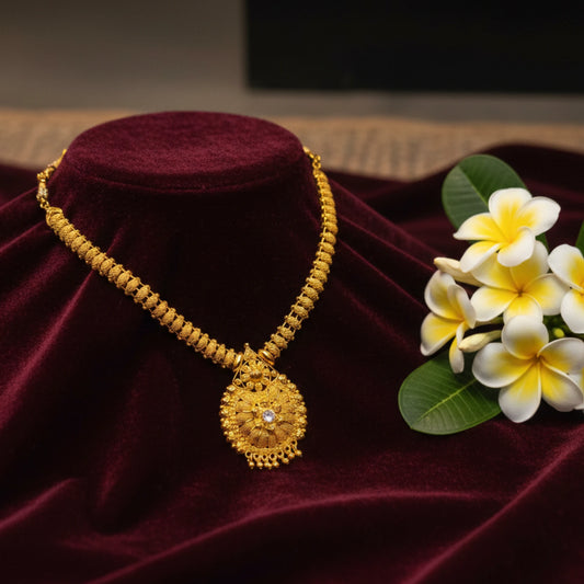 Gold plated necklace with a floral pendant on a beaded chain on a purple velvet stand with flowers on a dark background