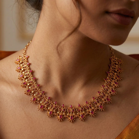 Close-up of a person wearing a gold plated traditional ruby choker necklace with red stones.