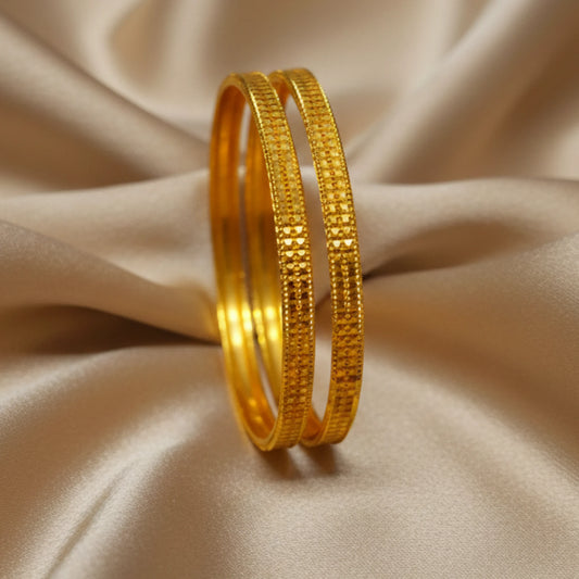 Two gold plated bangles on a beige fabric background