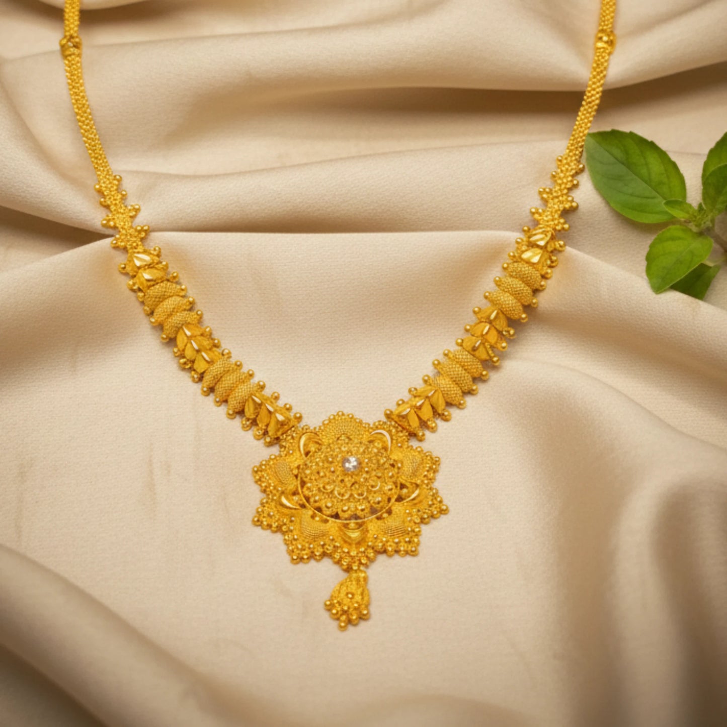 Gold plated necklace with intricate design and a floral mandala pendant on a beige fabric background