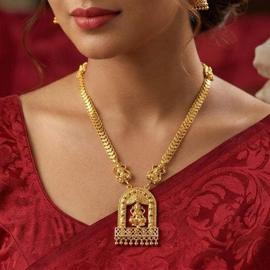 Gold plated necklace with a Lakshmi pendant worn by a person in a red outfit.