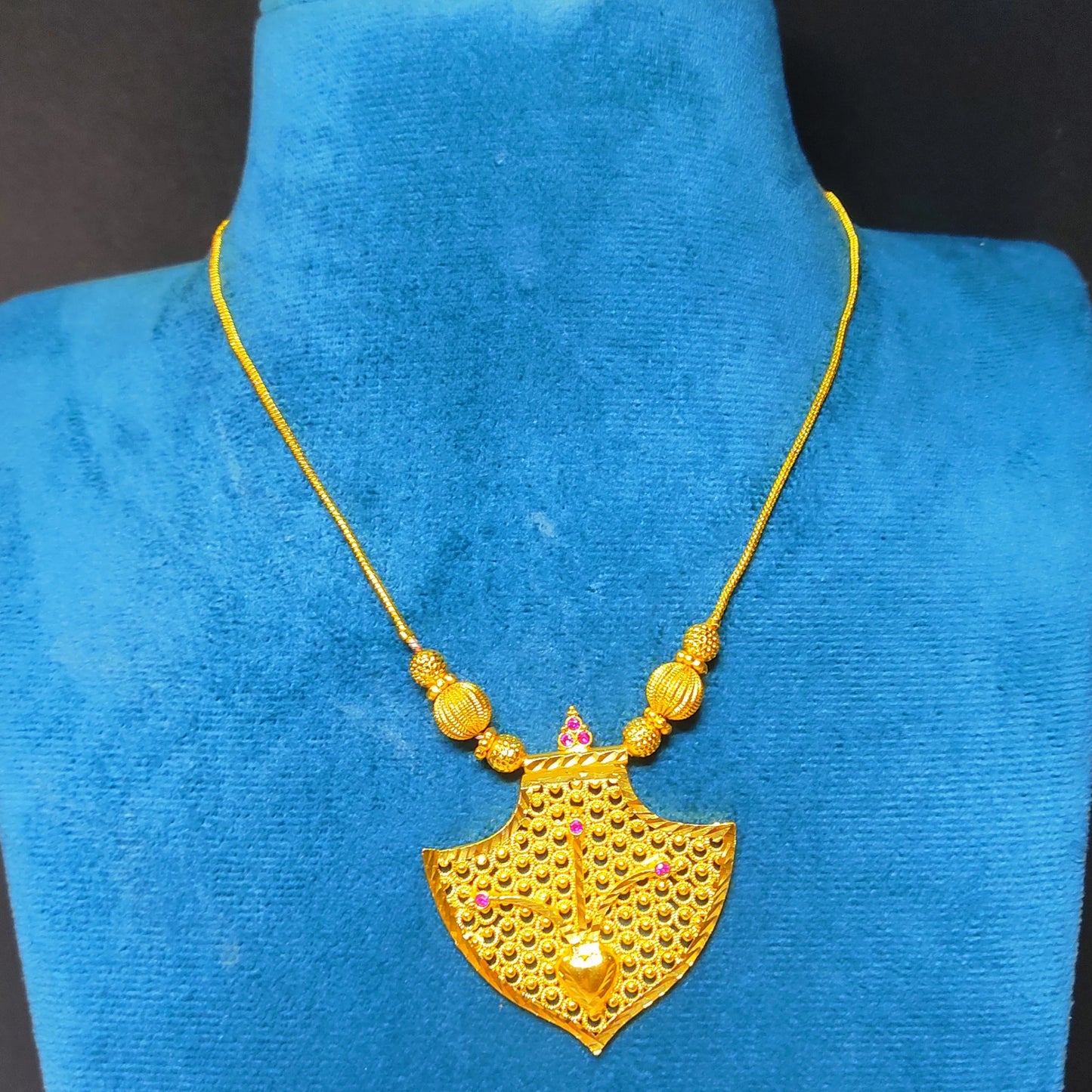 Fan shaped pendant with pink accents in a gold plated necklace