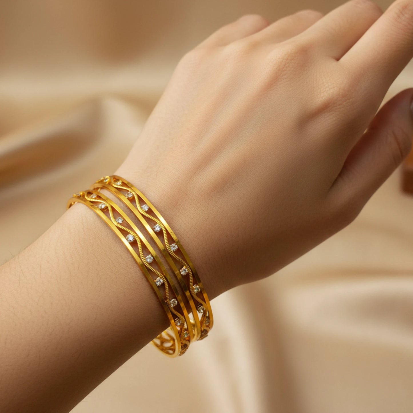 Gold plated bangles with small cz stones on a hand against a beige background