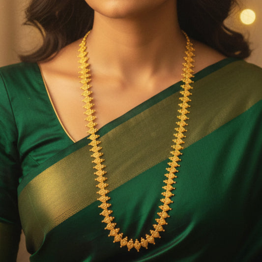 Woman wearing a green saree with a gold plated necklace against a blurred background