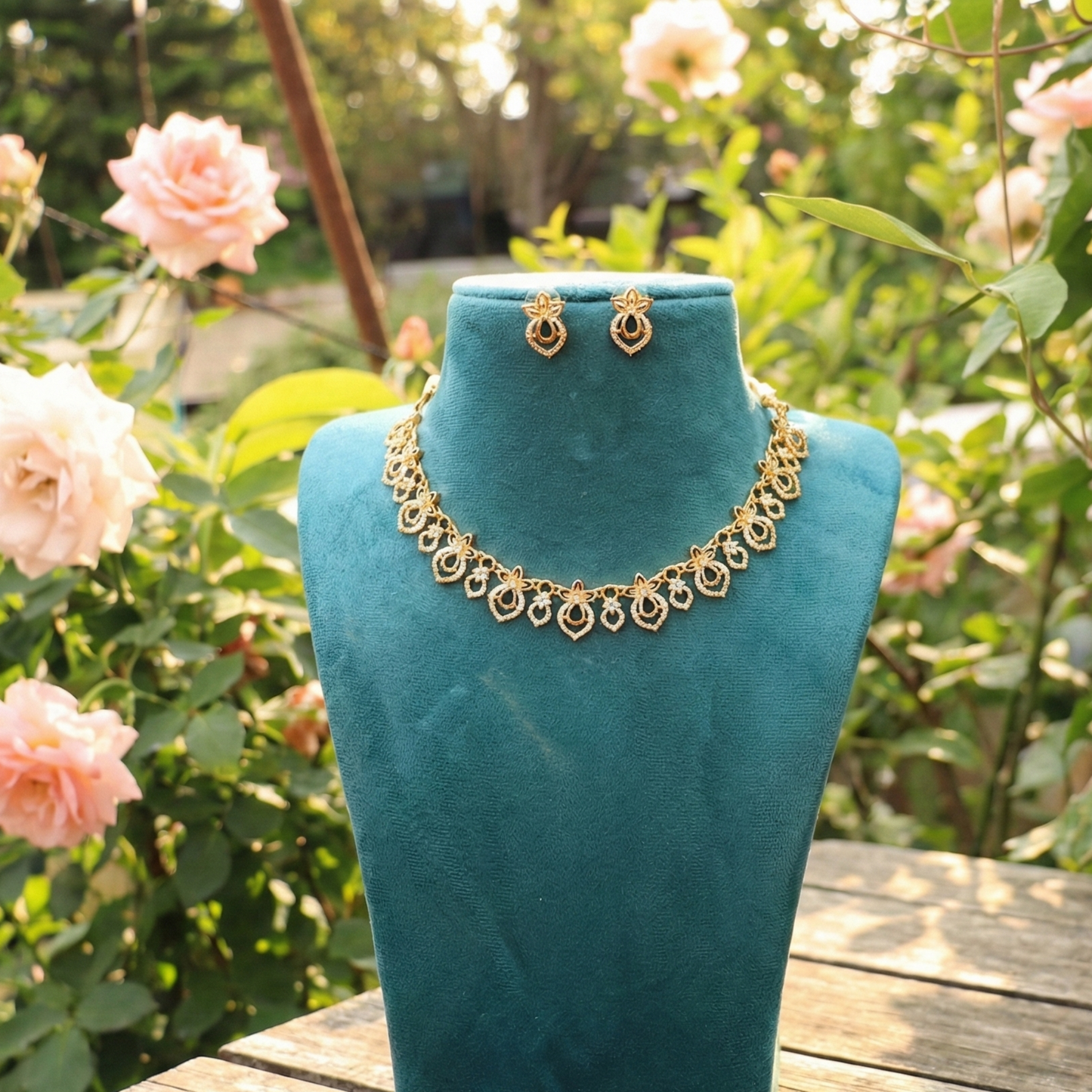 Gold toned necklace and earrings on a turquoise mannequin with a garden background