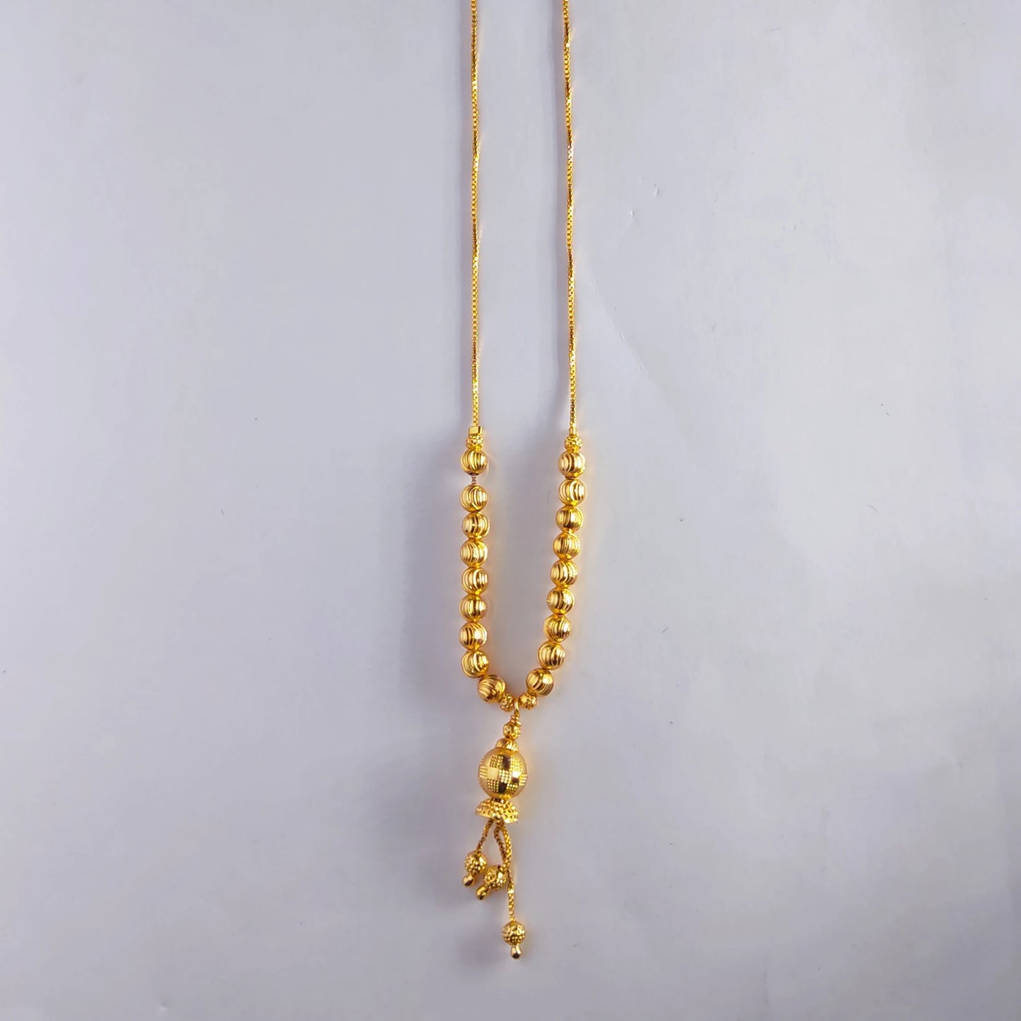 Gold plated necklace with beads on a light gray background