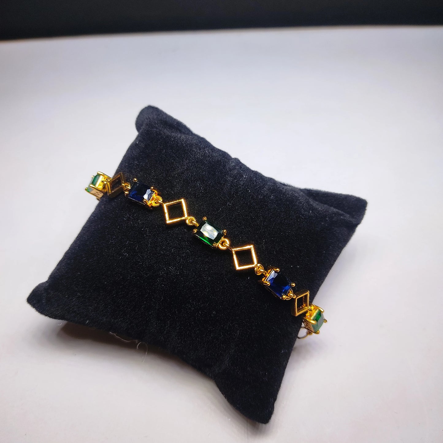 Gold Plated Bracelet with gemstone accents on a black jewelry pillow.