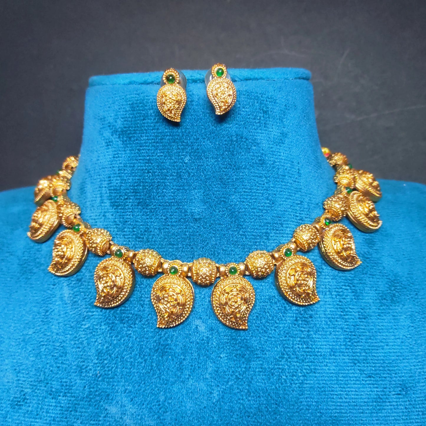 Antique Gold Finish necklace and earrings on a blue velvet stand