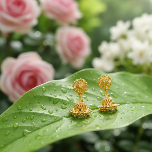 Gold plated earrings on a green leaf with flowers in the background