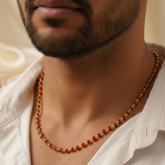 Close-up of a man wearing a red crystal mani mala with a blurred background.