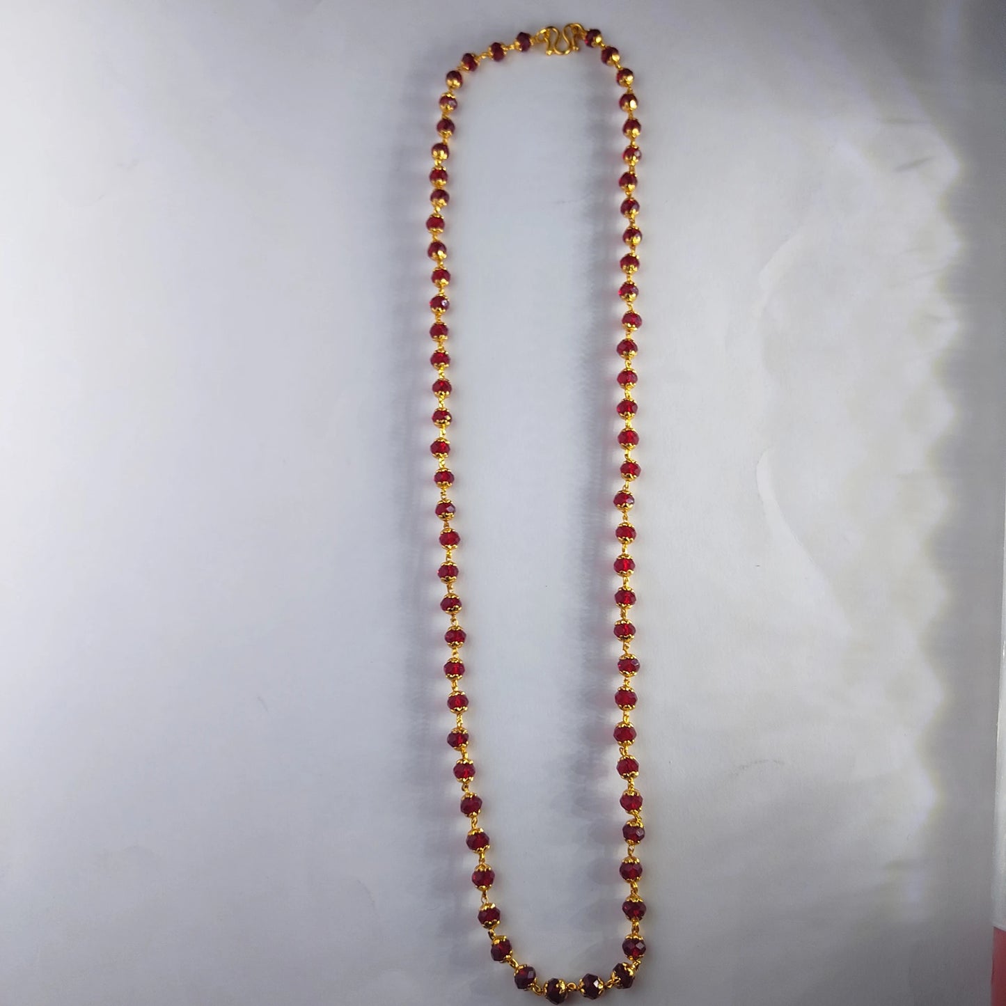 Beaded red crystal neckchain with a gold plated finish on a white background