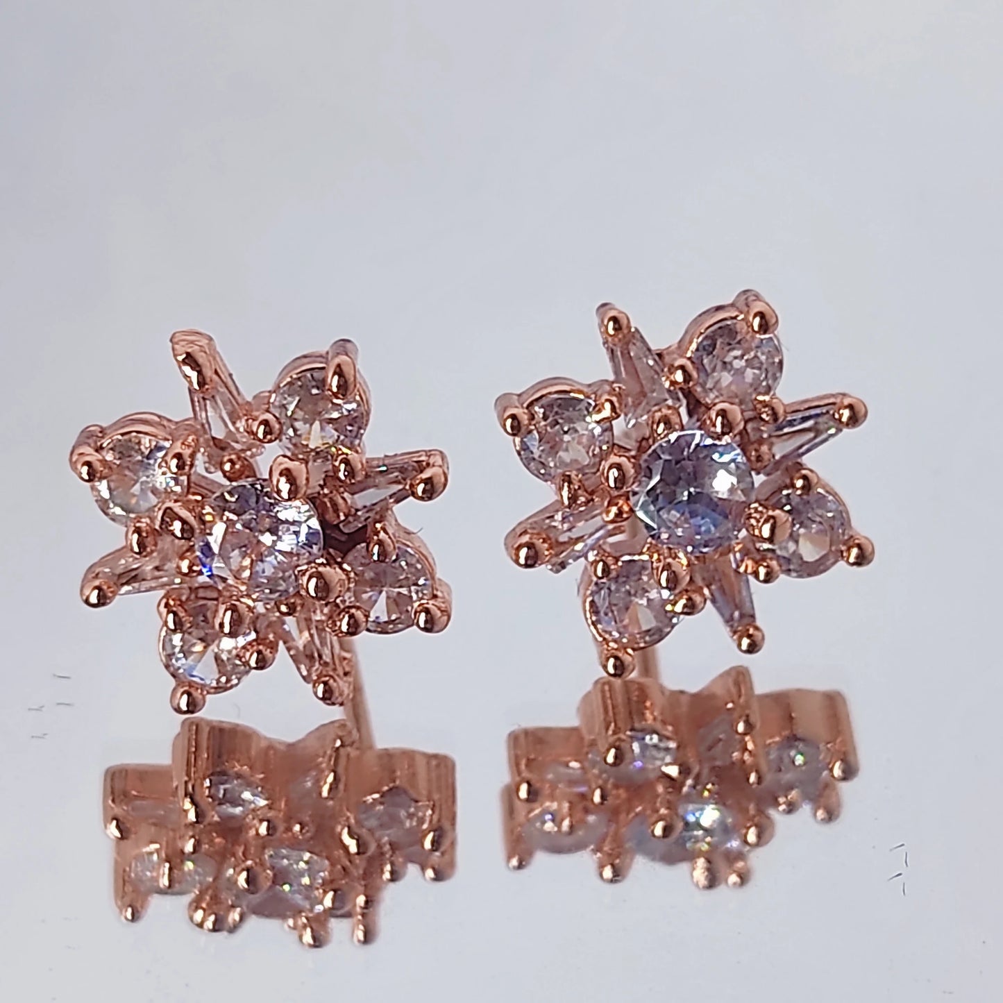 Rose gold earrings with gemstones on a light gray background