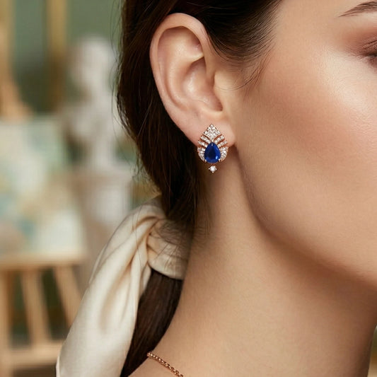 Close-up of a woman wearing a blue gemstone earring in rose gold plating with a blurred background