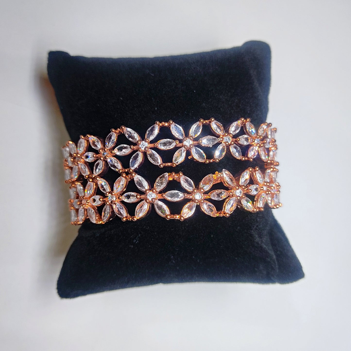 Rose gold and clear crystal bangles on a black velvet cushion