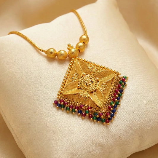 Gold plated necklace with a decorative pendant on a beige fabric background