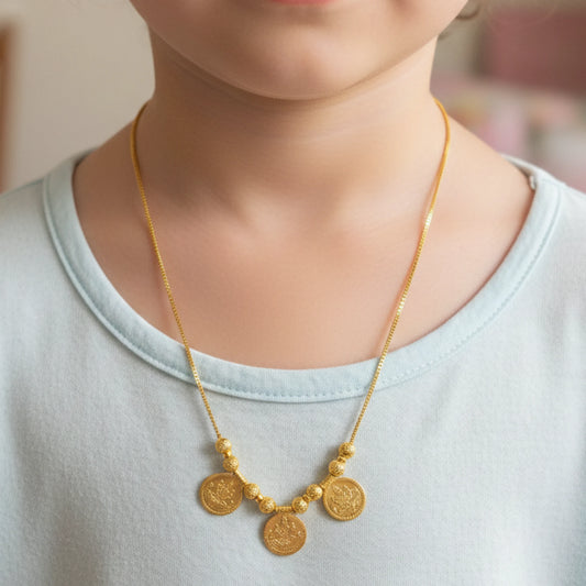 Gold plated necklace with lakshmi coin pendants on a person wearing a light blue shirt.