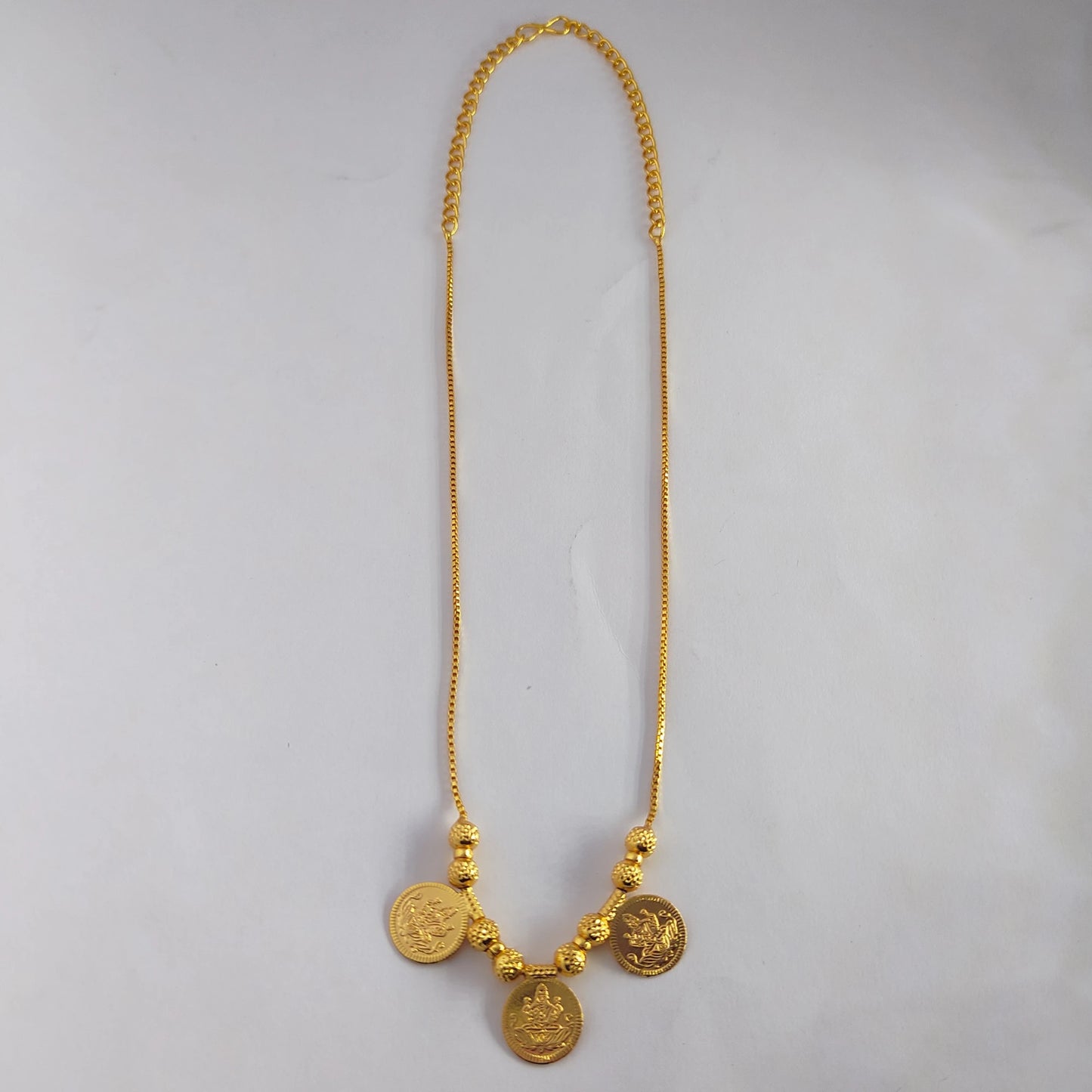 Gold plated Lakshmi coin necklace displayed on a white background